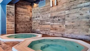 A spa area with two hot tubs against a wooden wall, a ventilation system, and a tiled floor. - BalticON Apartments Kasprowicza (Kolobrzeg)