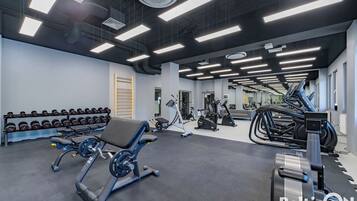 A gym with weightlifting equipment, treadmills, and dumbbells.