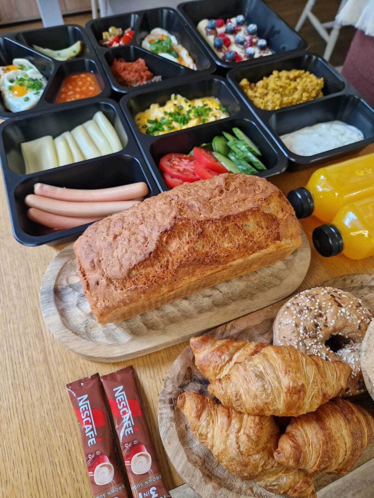 Un buffet de petit-déjeuner proposant une variété d’aliments, notamment du pain, des viennoiseries et une boisson au café.