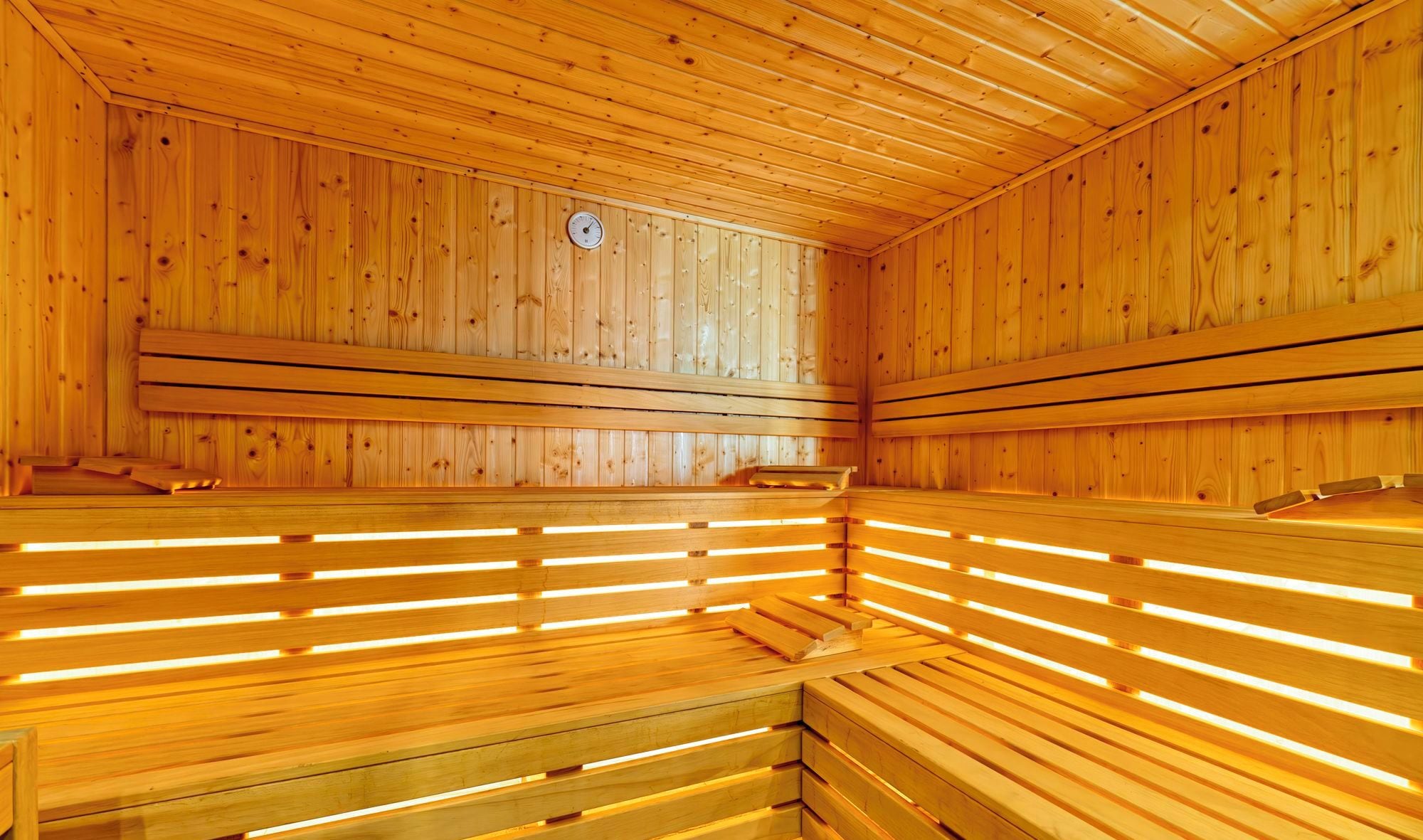 Una sauna con bancos de madera y un termómetro a la vista.