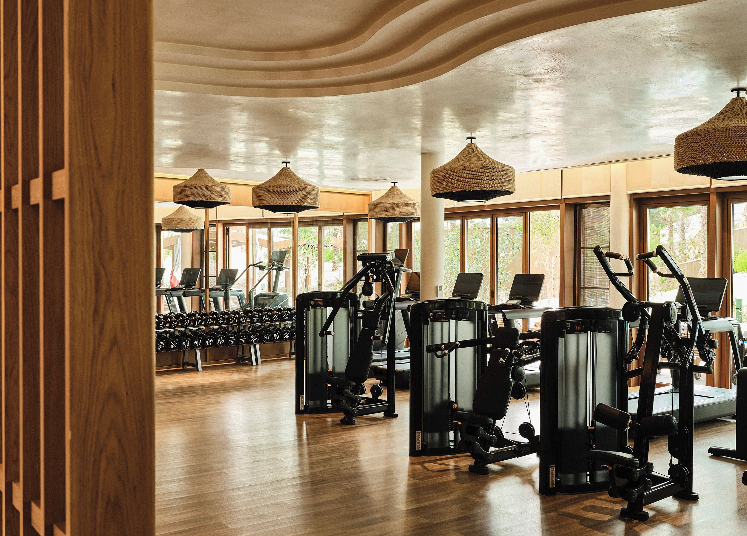 Un gimnasio con cintas de correr, máquinas de pesas y mancuernas.