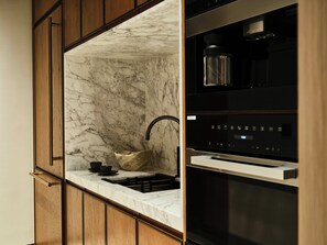 A kitchen with a marble countertop, wooden cabinets, a stainless steel range hood, and a built-in oven. - Four Seasons Resort And Residences Red Sea At Shura Island (Umluj)