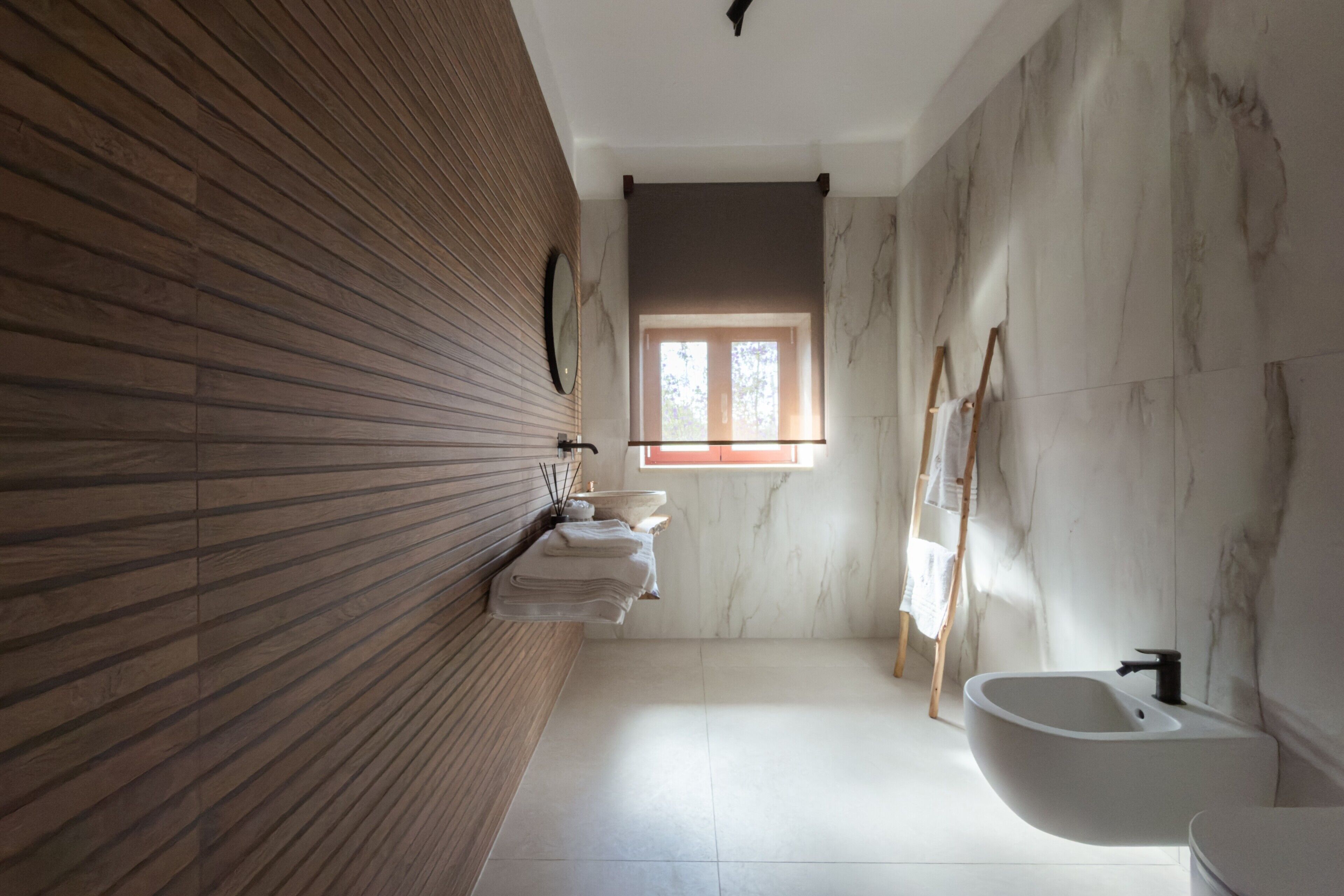 Ein Badezimmer mit einer Holzvertäfelung, einem мраморном Waschbecken und einem Fenster für natürliches Licht.