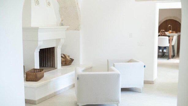 Un intérieur moderne avec une cheminée, des meubles blancs et une vue sur une autre pièce.