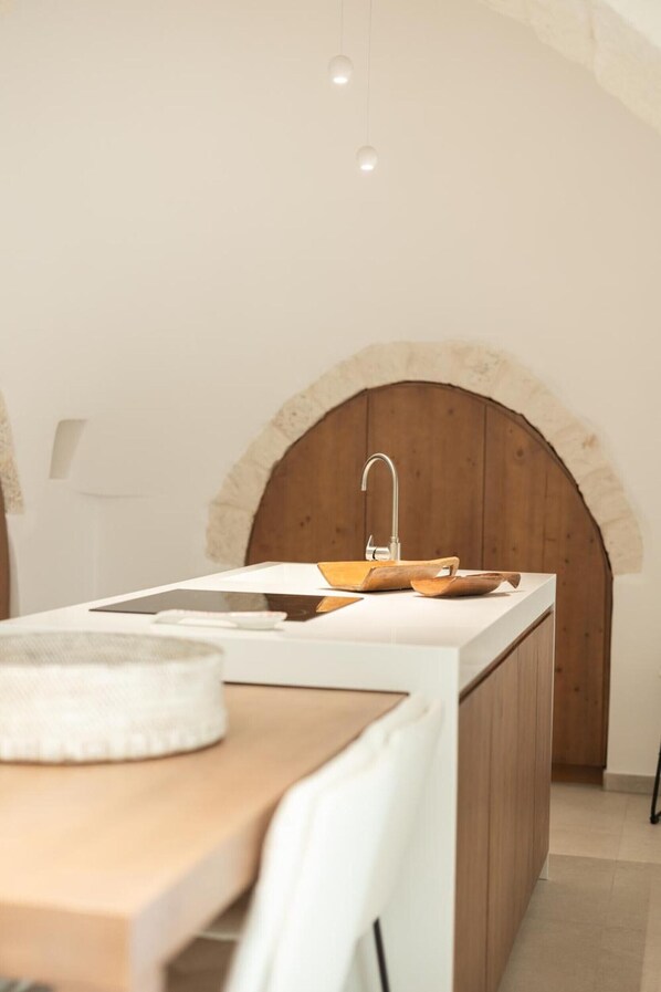 A kitchen with a wooden countertop, white sink, and a rustic stone archway.