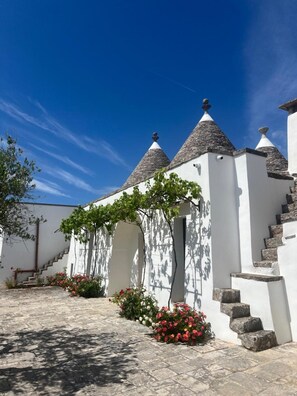 A white building with stone roofs and a staircase leading to an entrance.