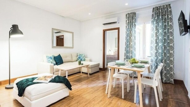 Uma sala de estar moderna com um sofá, mesa de centro, mesa de jantar com cadeiras e um abajur.