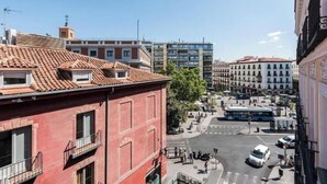 Vista da rua com edifícios, um ônibus e uma faixa de pedestres.