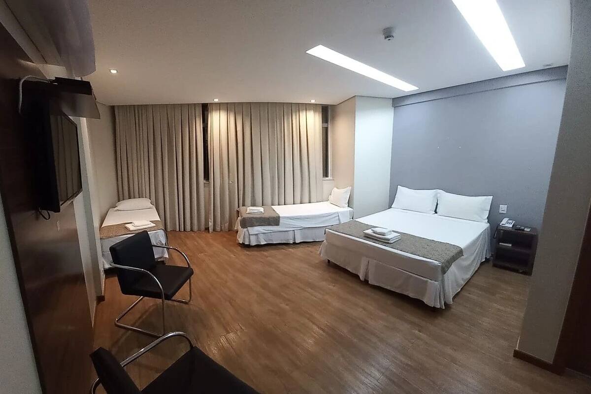 Una habitación de hotel con dos camas, un escritorio, una silla y un televisor.