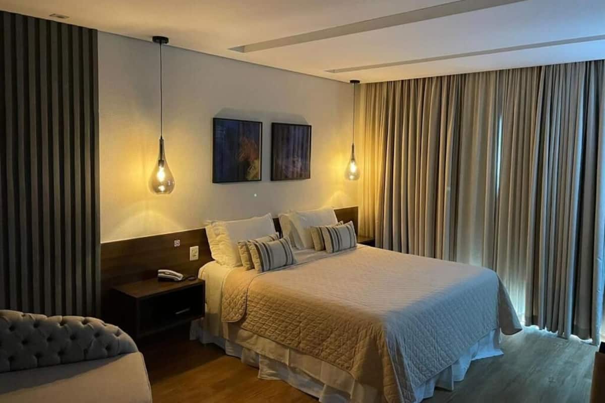 Una habitación de hotel con una cama grande, dos mesitas de noche y una silla.
