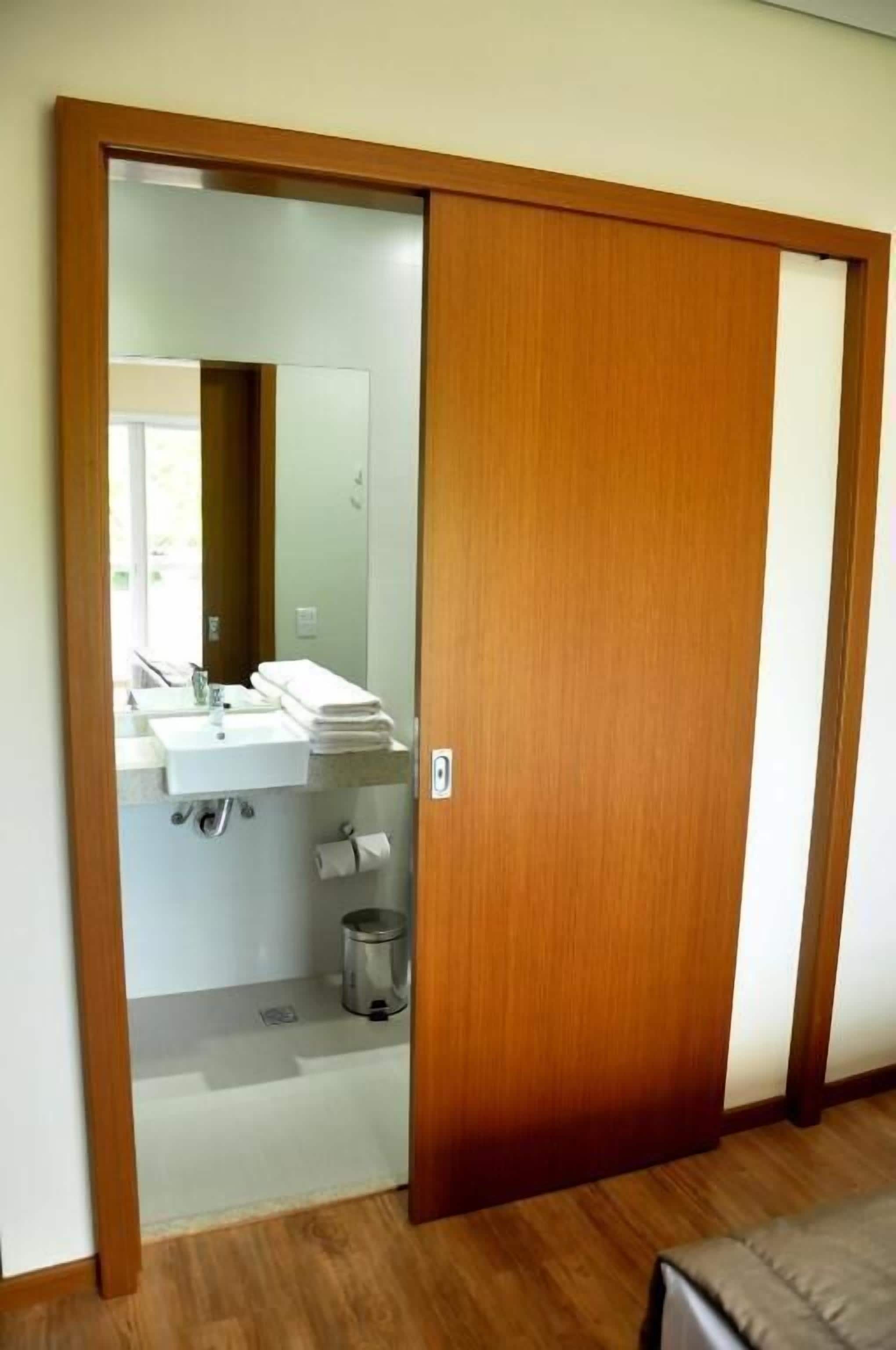Una habitación con un armario de madera, un espejo, un lavabo y un inodoro.