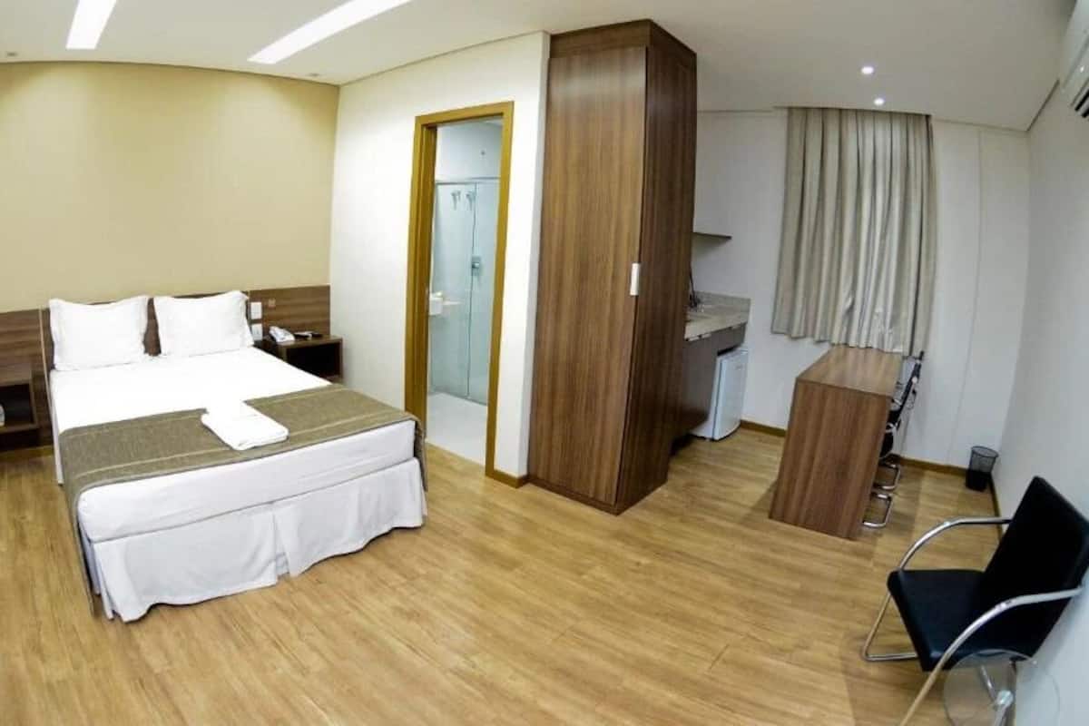 Habitación de hotel con cama, escritorio, silla, armario y puerta de baño.