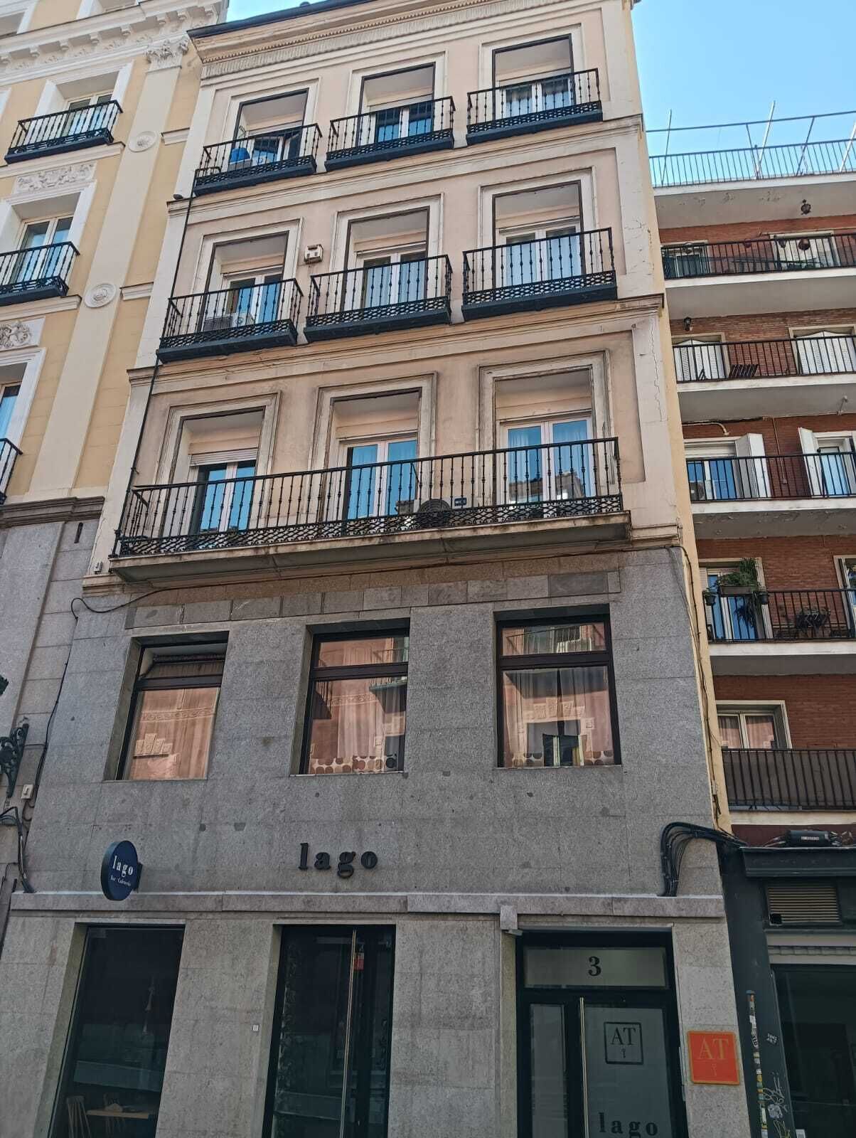 A multi-story building with balconies, a sign reading 'Lago,' and a ground-level entrance with a door marked '3.'