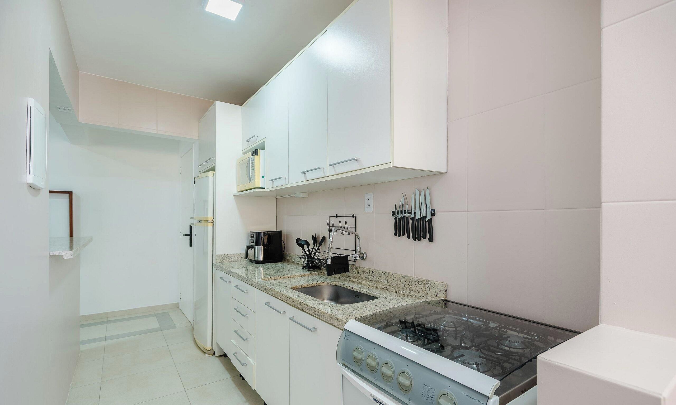 A compact kitchen with white cabinets, a gas stove, a microwave, and a coffee maker.