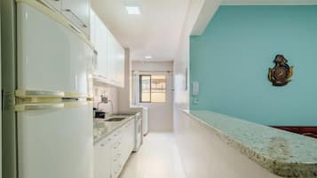 Una cocina con armarios blancos, encimera de granito y un reloj en la pared.