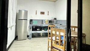 Une cuisine équipée d’un réfrigérateur, d’un four à micro-ondes et d’une table à manger en bois.