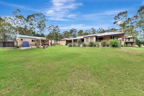 A row of single-story buildings with attached garages, surrounded by a grassy area and trees. - Vine & Valley Retreat (North Rothbury)