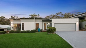 A modern two-story house with a garage, a well-maintained lawn, and a clear sky. - Resort Style Home with Plunge Pool (Cessnock)