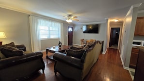 A living room with a sofa, two armchairs, a coffee table, and a ceiling fan.