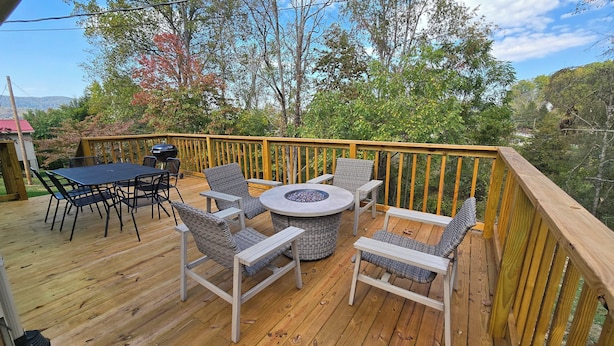 A wooden deck with a round table and wicker chairs, surrounded by a wooden railing.