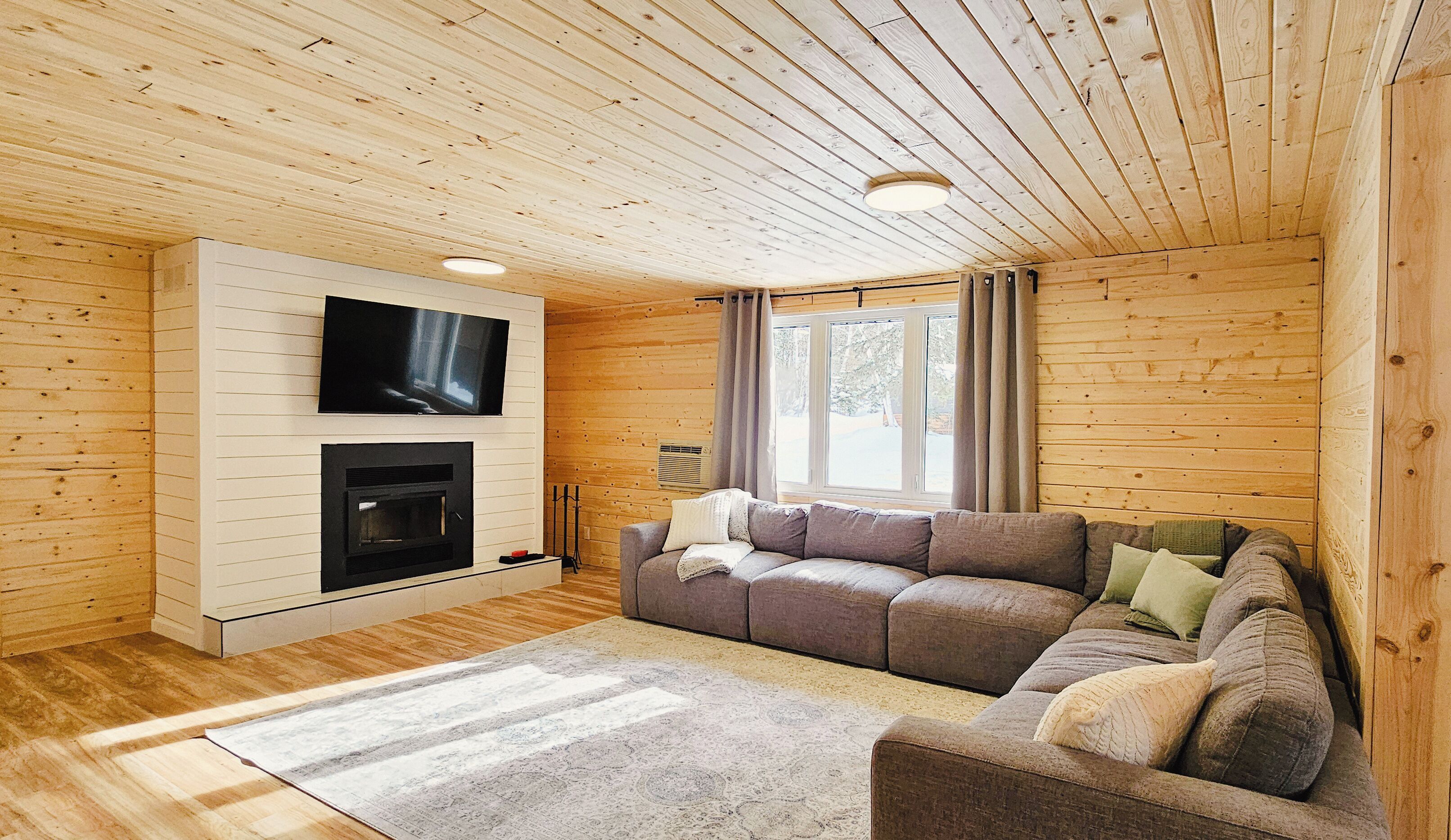 Een gezellige woonkamer met een open haard, een aan de muur bevestigde televisie en een comfortabele bank.