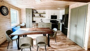 A wooden interior with a dining table, chairs, a kitchen area, and a large cabinet. - Faloma Lakeside Cabins (Faloma)
