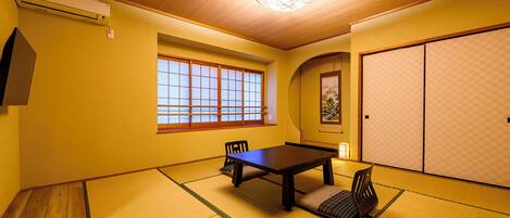 A traditional Japanese room with tatami flooring, a sliding door, and a window with wooden frames.