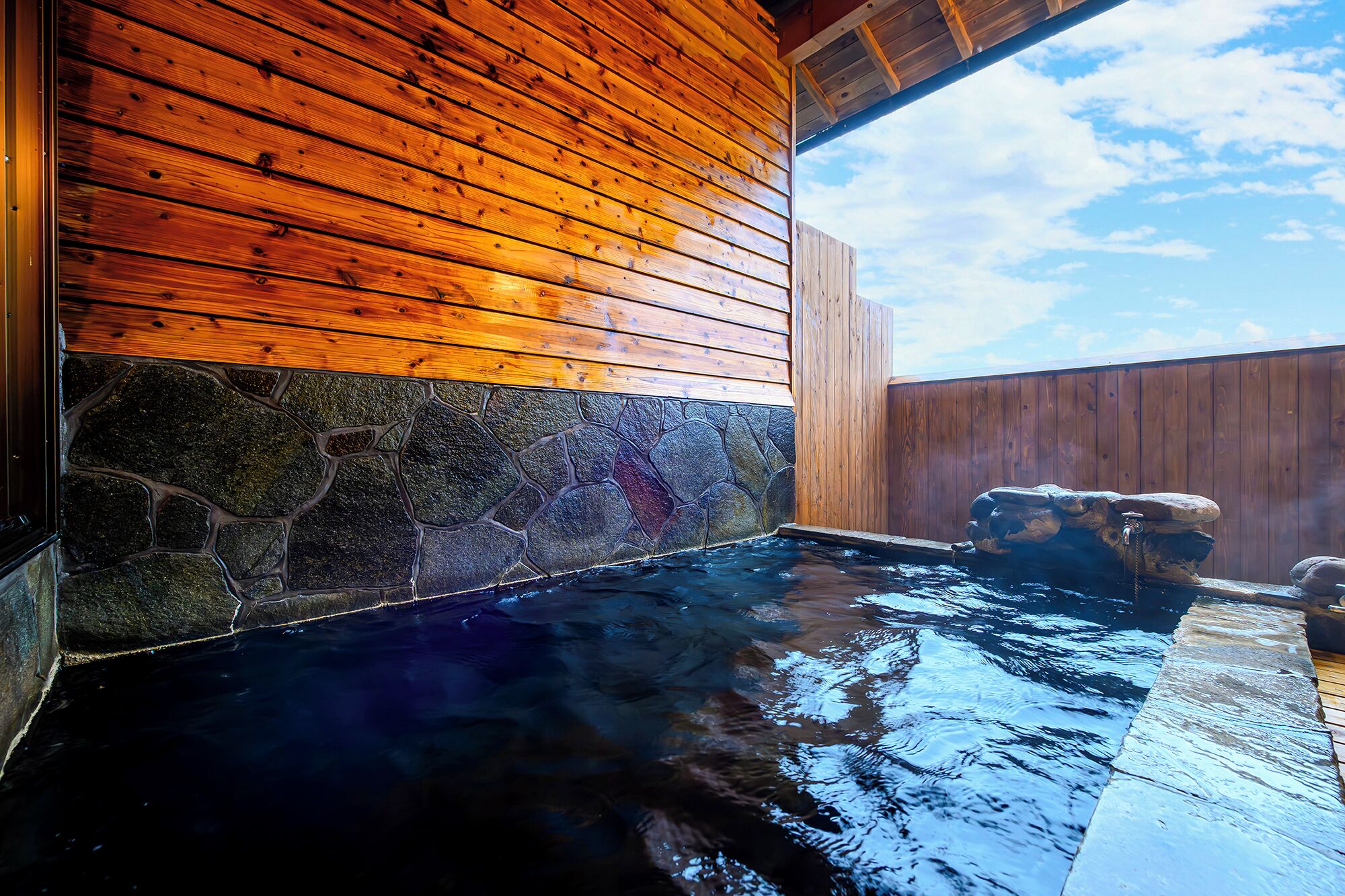 A hot spring area with wooden walls and a stone wall.