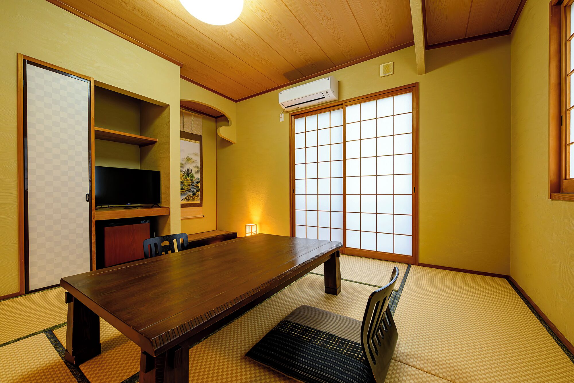 A traditional Japanese room with tatami flooring, a low table, a television, and a shoji screen.