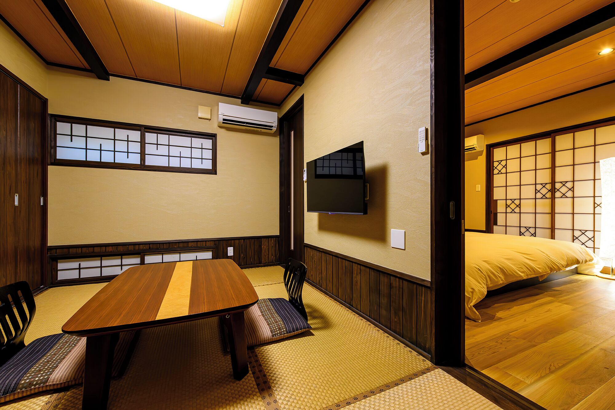 A traditional Japanese room with tatami flooring, a low table, and a bed with a sliding door.