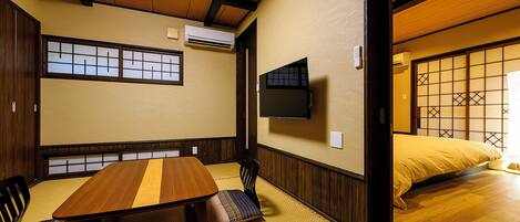 A traditional Japanese room with tatami flooring, a low table, and a bed with a sliding door.