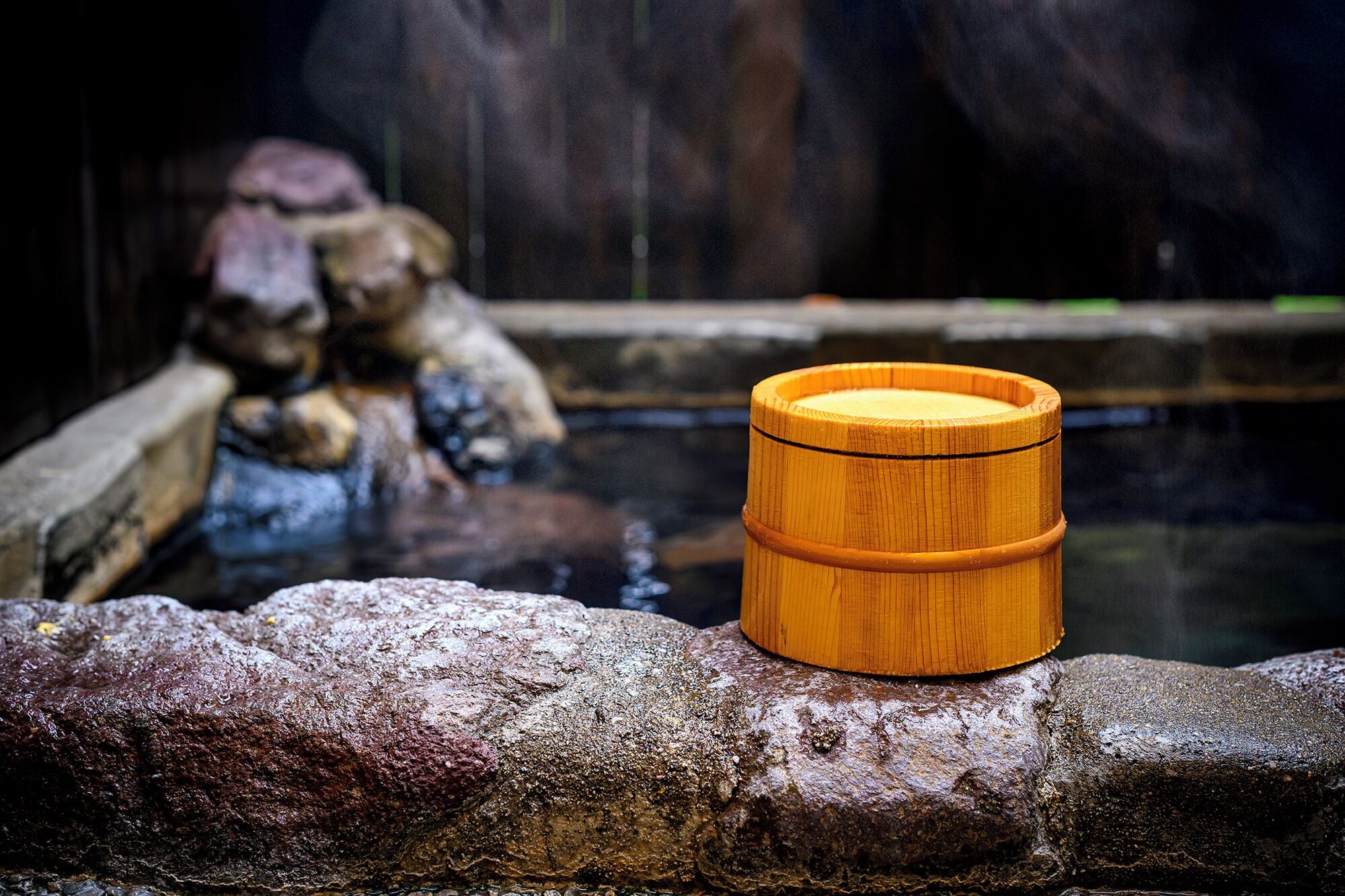 A wooden barrel on a stone ledge by a body of water with rocks and a waterfall in the background.