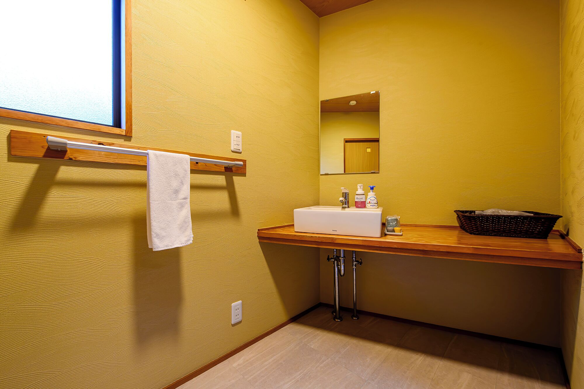 A bathroom with a wooden vanity, a white sink, a mirror, and a towel rack.