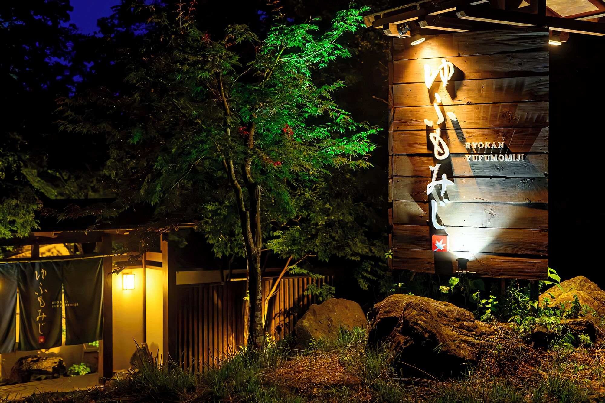 A wooden structure with signage, surrounded by rocks and greenery.