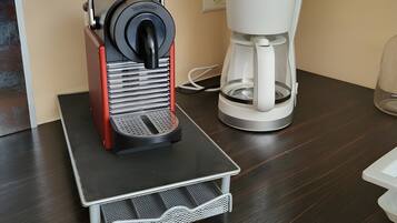 Eine Kaffeemaschine auf einer Arbeitsplatte, daneben eine weiße Kaffeekanne.
