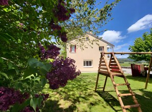 Ein Haus mit einer Holzschaukel und einer Kletterleiter im Garten.
