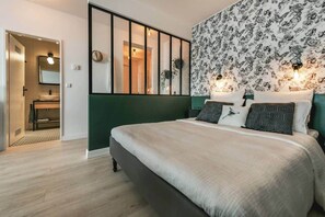 Ein modernes Schlafzimmer mit einem großen Bett, einer grünen Akzentwand und einem floralen Wandpapier.