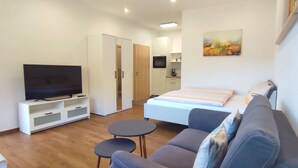 A modern living room with a flat-screen TV, a sofa, a small table, and a bed. - Vacation apartment 'Wiesenpanorama' (Münstertal/Schwarzwald)
