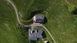 An aerial view of a property with two main buildings, a winding road, and surrounding green fields. - Vacation apartment 'Wiesenpanorama' (Münstertal/Schwarzwald)