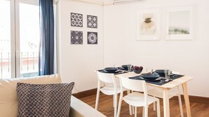 A dining area with a white table set for four, white chairs, and a blue curtain on a window. - Bright and spacious apartment in downtown Madrid (Madrid)