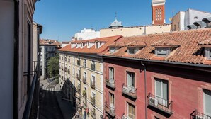 A narrow street with buildings featuring red-tiled roofs and balconies. - Bright and spacious apartment in downtown Madrid (Madrid)