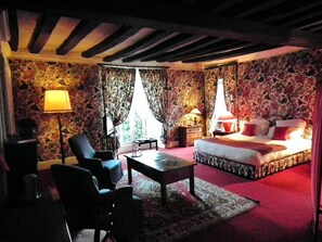 A bedroom with a bed, two chairs, a table, and a lamp. - le relais cicero (La Flèche)