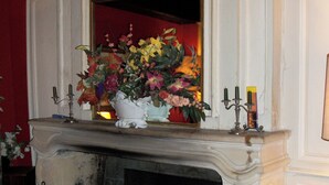 A fireplace with a floral arrangement, candles, and a mirror above it. - le relais cicero (La Flèche)