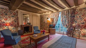 A cozy room with a fireplace, a large bed, two armchairs, and a television. - le relais cicero (La Flèche)