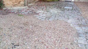 A cobblestone courtyard with a stone wall and a door. - le relais cicero (La Flèche)