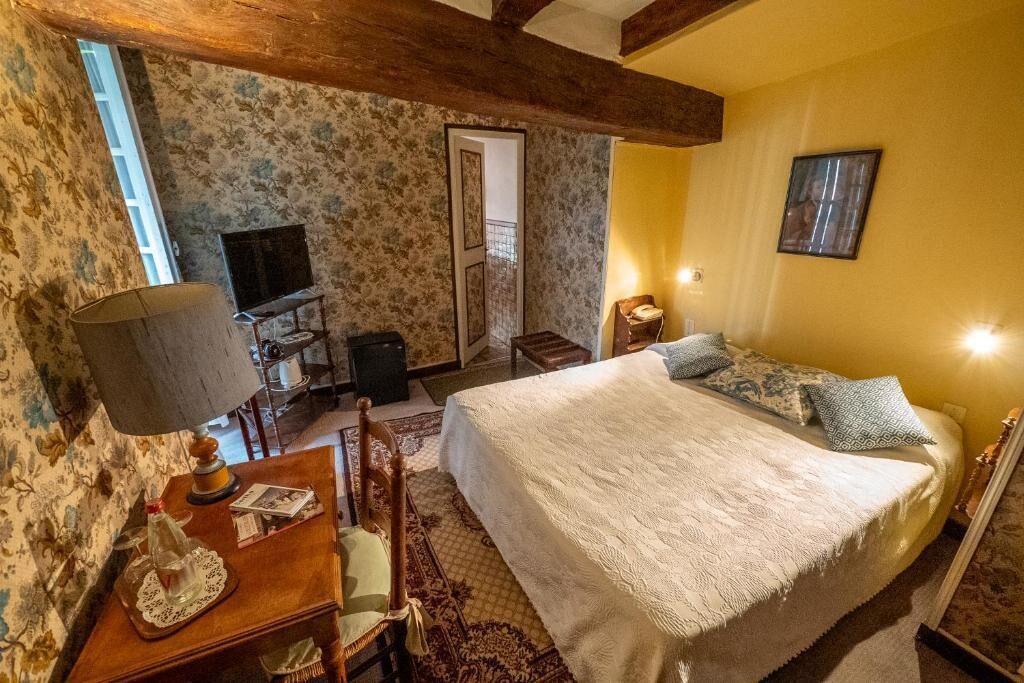 Une chambre confortable avec un grand lit, un bureau en bois avec une lampe, une chaise et un téléviseur.