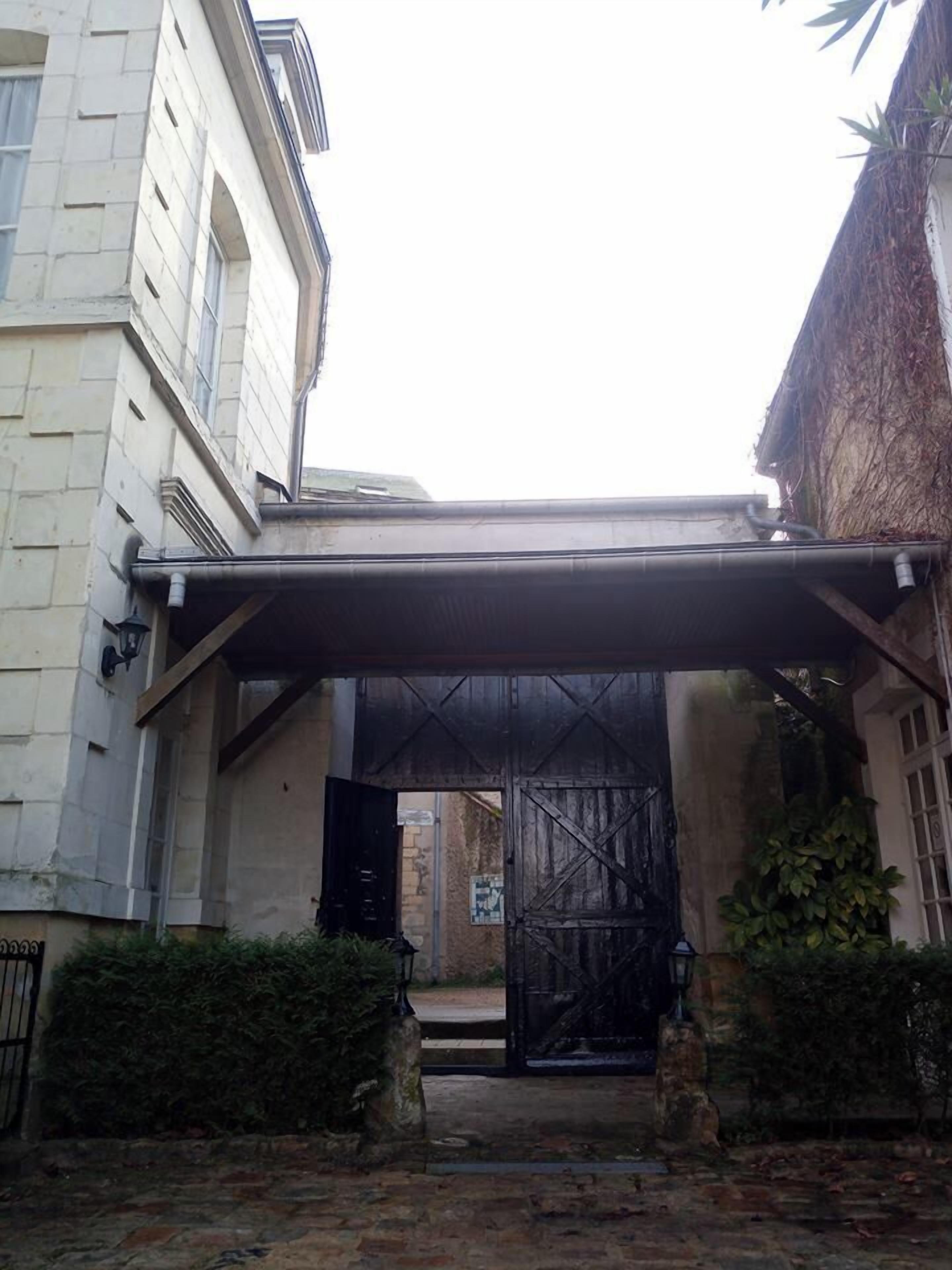 A building entrance with a covered walkway, stone steps, and a metal gate.