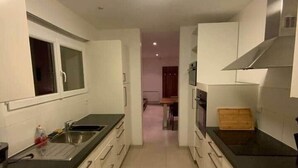 A narrow kitchen with white cabinets, a black countertop, and a stainless steel range hood. - ★ House 49m2 ★ Pessac ★  Netflix ★ Bus ★ Train (Pessac)