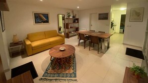 A living room with a yellow sofa, a round coffee table, and a dining table with chairs. There is a bookshelf and a mirror on the wall. - ★ House 49m2 ★ Pessac ★  Netflix ★ Bus ★ Train (Pessac)