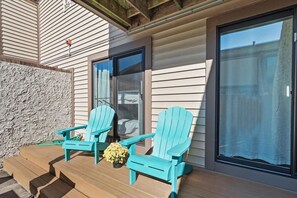 Eine Holzterrasse mit zwei türkisfarbenen Adirondack-Stühlen und einem kleinen Topfpflanzen.